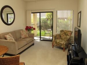 A cozy living room with a sofa, armchair, and sliding glass door leading to an outdoor area.