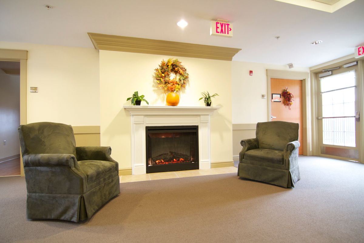 A cozy living room with a decorated fireplace and two armchairs.