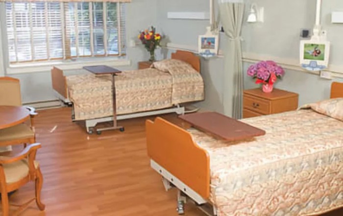 A hospital room with two beds and floral decorations.