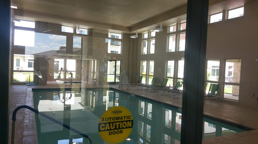 A serene indoor pool area illuminated by natural light, showcasing a caution sign for safety.