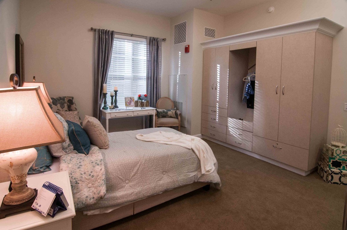 A cozy bedroom interior with a bed, wardrobe, and window with curtains.