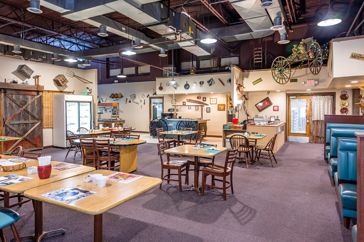 A cozy restaurant dining area with wooden tables, chairs, and rustic decor.