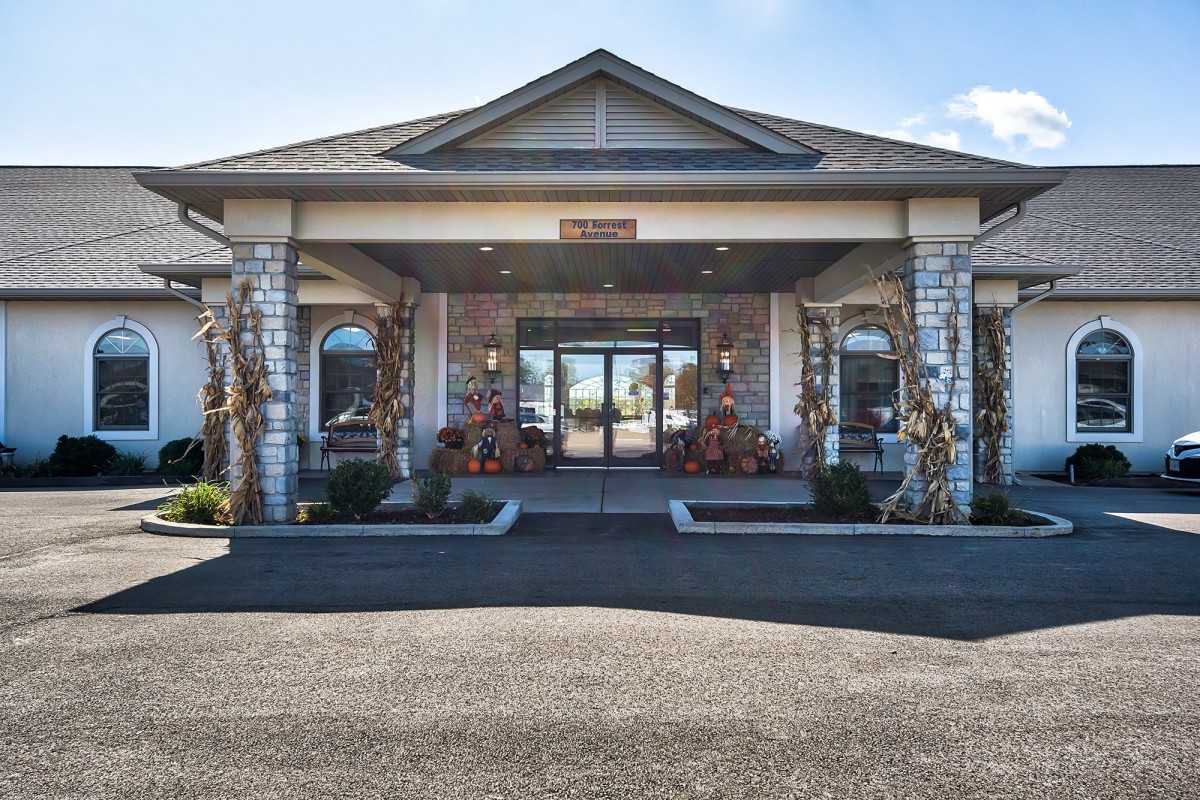 A front view of a building entrance with columns and a peaked roof.