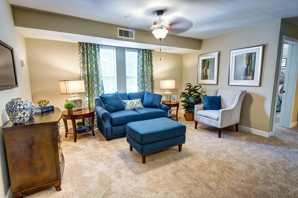 A cozy living room featuring a blue sofa and ottoman, complemented by an armchair and decorative elements.
