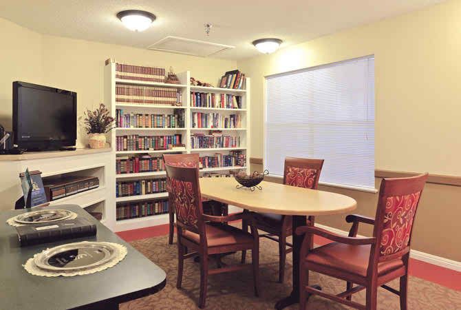A cozy library with bookshelves, a round table, and chairs for reading.