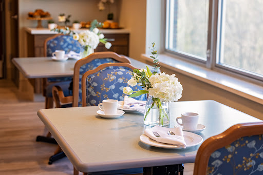 A cozy dining area with elegantly set tables adorned with fresh flowers.