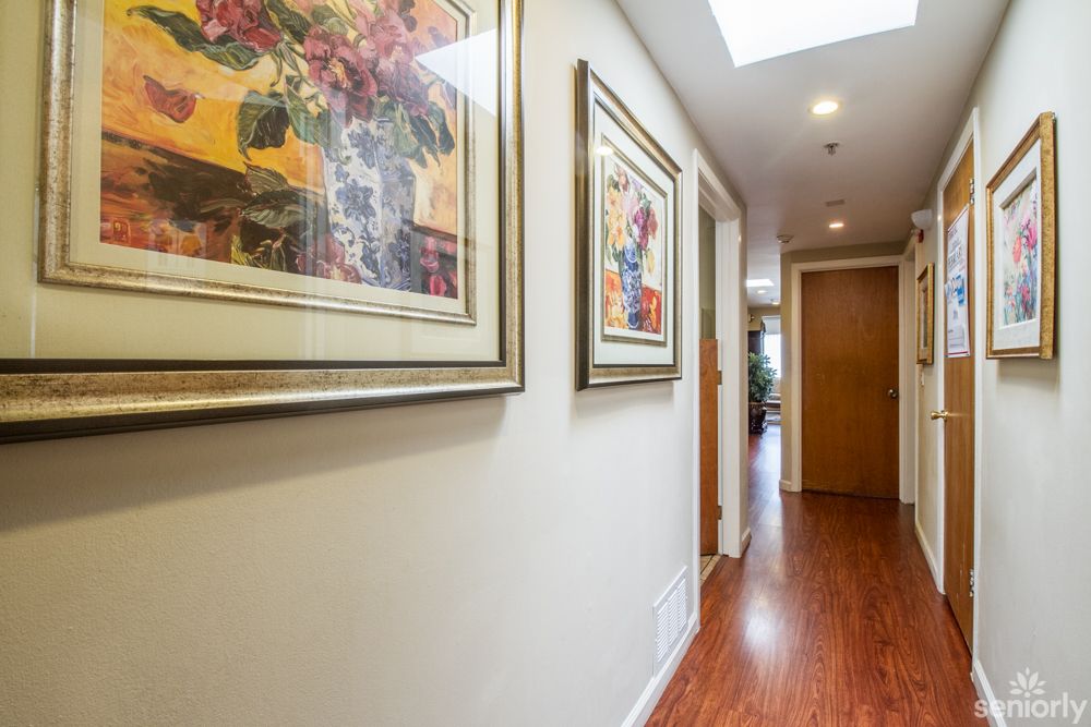 A hallway with framed artwork and wooden flooring.