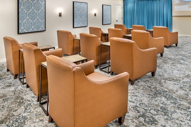 A neatly arranged conference room with rows of comfortable chairs and small tables.