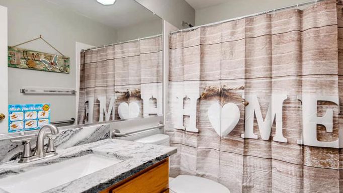 A bathroom with a wooden-themed shower curtain and a well-organized countertop.