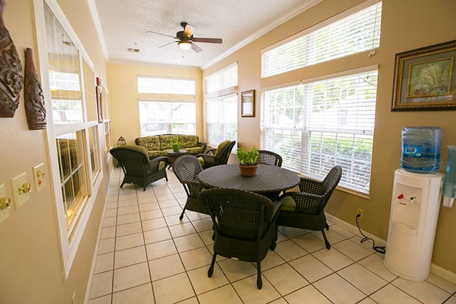 A cozy sunroom with rattan furniture and large windows.