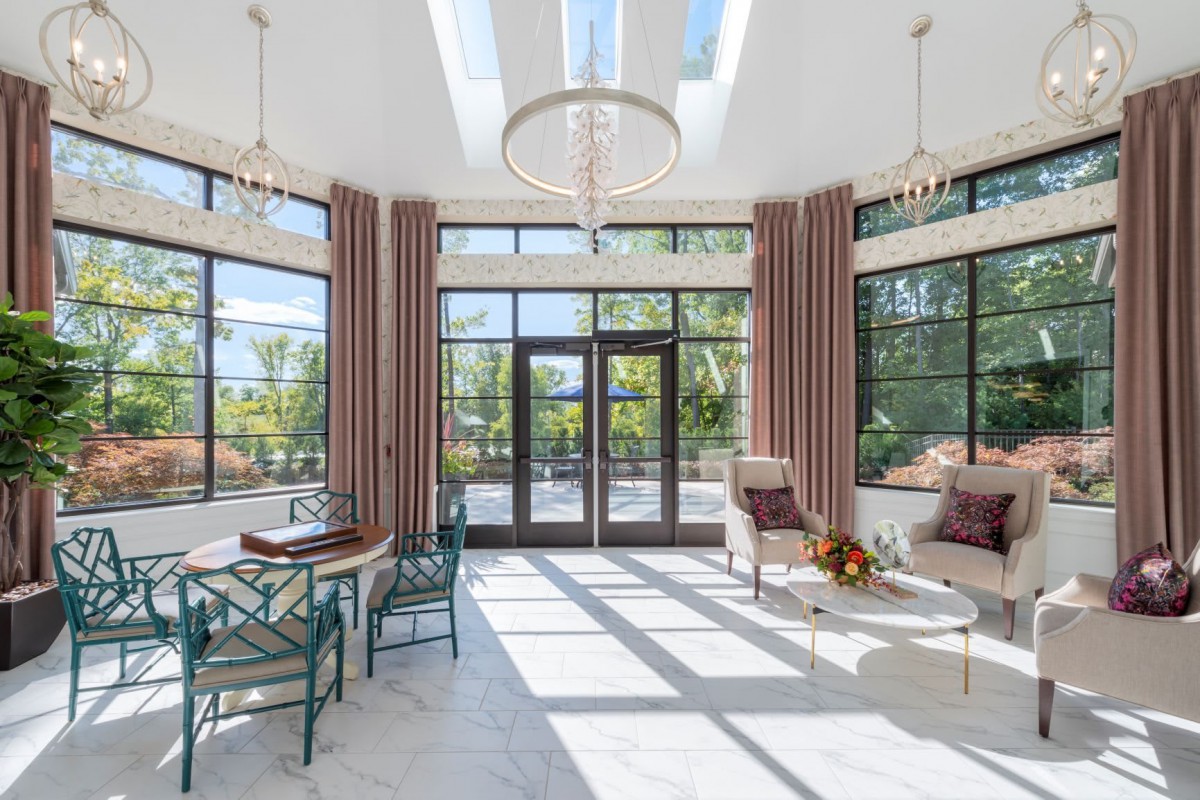 A modern living room with large windows and skylights, featuring elegant furniture and abundant natural light.