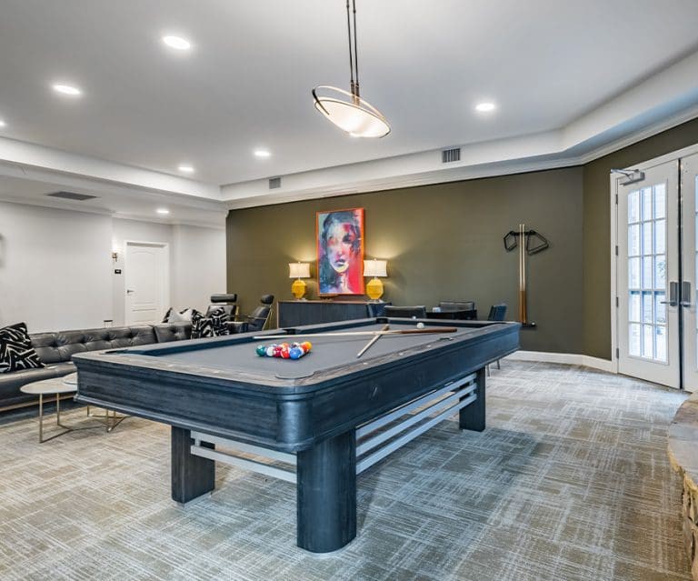 A modern game room featuring a sleek pool table under stylish lighting, designed for recreation and relaxation.