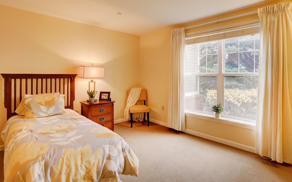 A cozy bedroom with warm lighting and a large window letting in natural light.