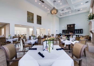 An elegant restaurant interior featuring neatly arranged tables and chairs, with a decorative chandelier hanging from the ceiling.