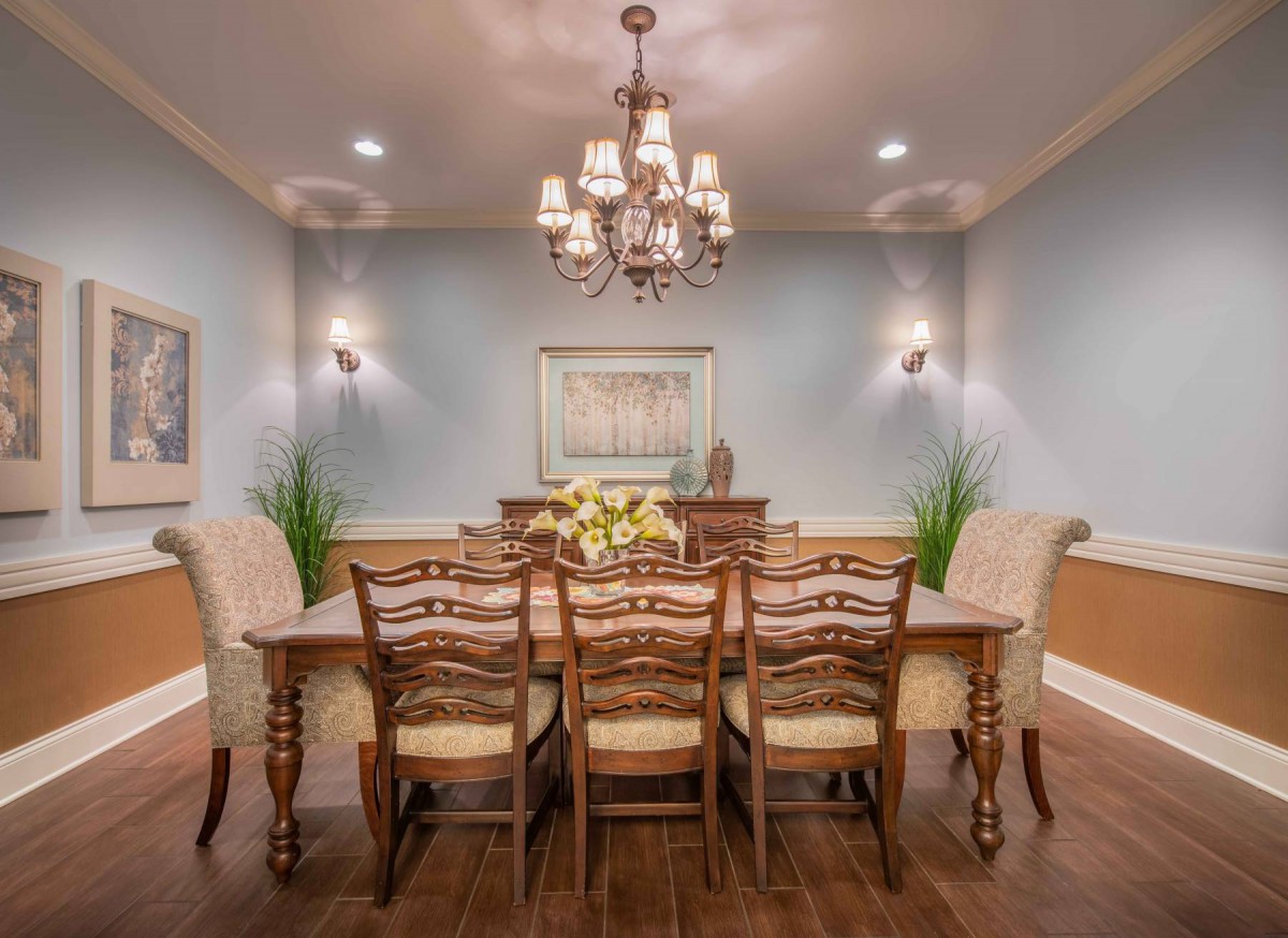 Elegant dining room with a central wooden table and chandelier lighting.