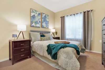A cozy bedroom with a neatly made bed, adorned with colorful artwork and elegant lamps.
