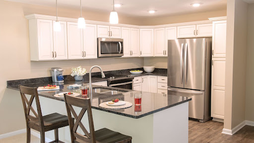 A modern kitchen featuring white cabinets, stainless steel appliances, and a stylish island with seating.
