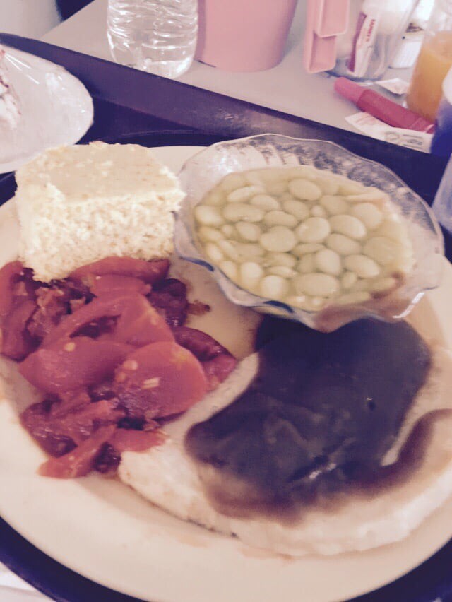 A plate of food featuring cucumber salad, cheese, peppers, and a dark sauce.