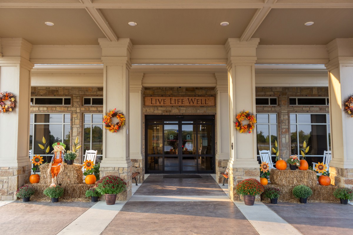 An inviting building entrance decorated with autumn-inspired wreaths, pumpkins, and colorful mums.