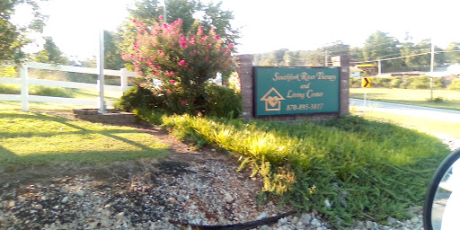 Welcome sign for a community center surrounded by vibrant flowers and greenery.