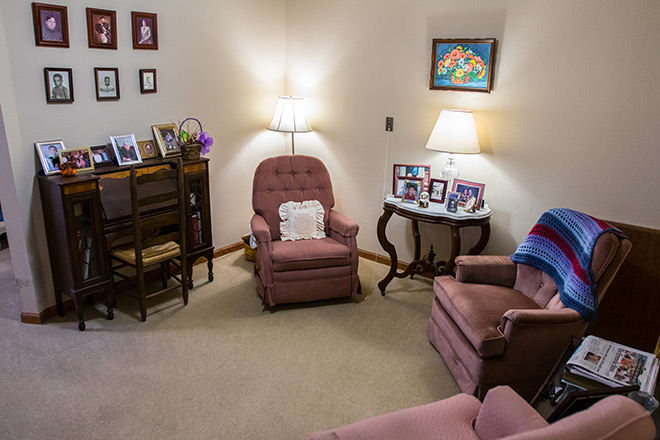 A cozy living room with vintage armchairs, decorative lamps, and family photos.