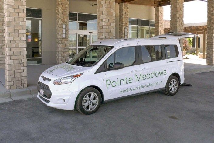 A white van with the words 'Pointe Meadows' parked in front of a building.