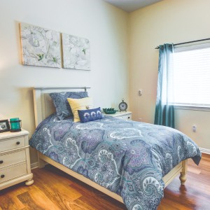 A cozy bedroom with a single bed, decorative pillows, and soft lighting.