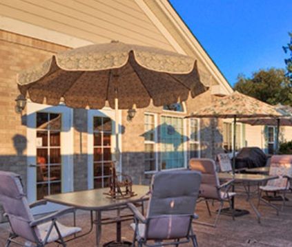 A sunny outdoor patio with tables, chairs, and umbrellas.