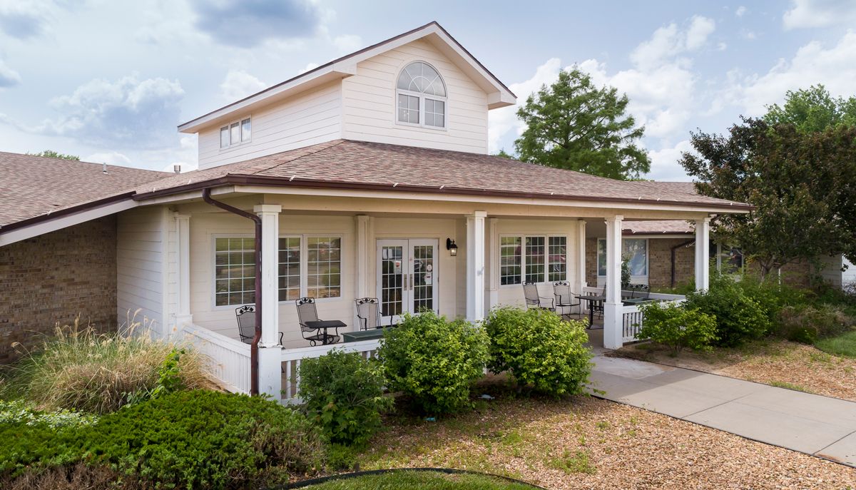 A spacious two-story house with a front porch and well-maintained landscaping.
