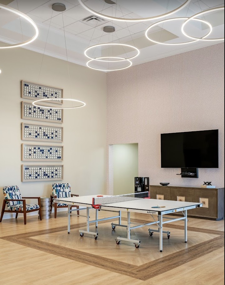 A modern conference room featuring a central table, seating, contemporary artwork, and a mounted television.