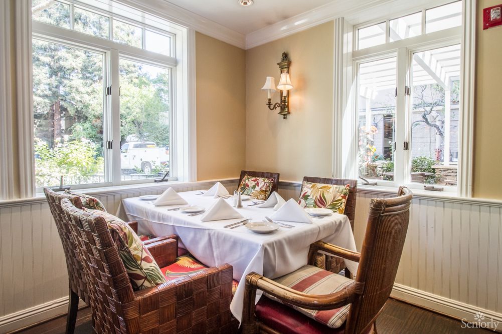 A cozy dining room with a neatly set table and comfortable seating by the windows.