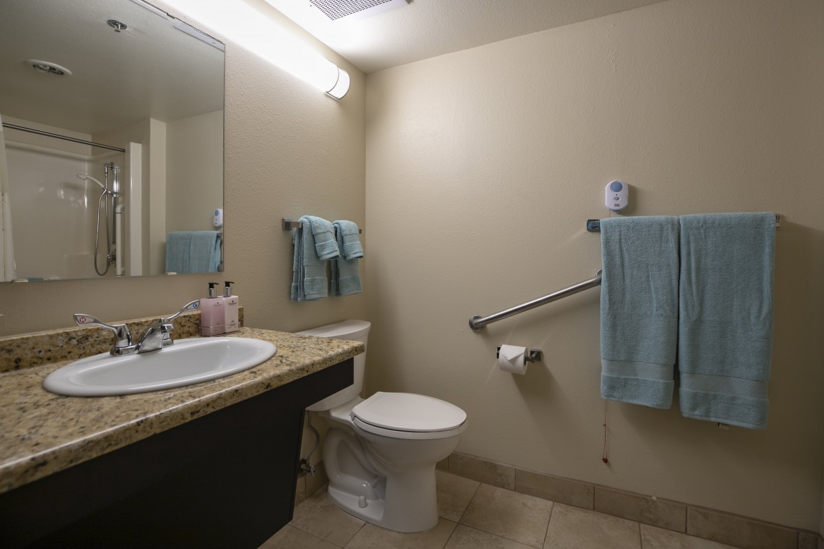 A clean and simple bathroom with a sink, toilet, and mounted towels.