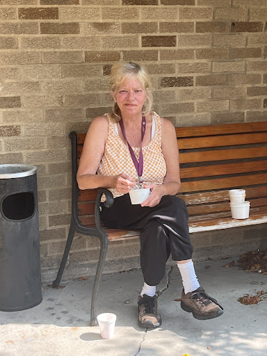 A person enjoying a snack while seated on a bench in an outdoor area.