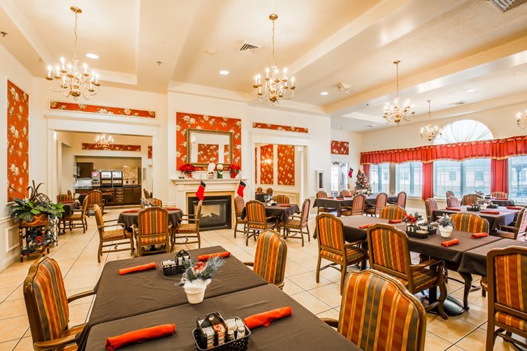 A spacious and elegantly decorated restaurant interior with multiple tables, chairs, and chandeliers.