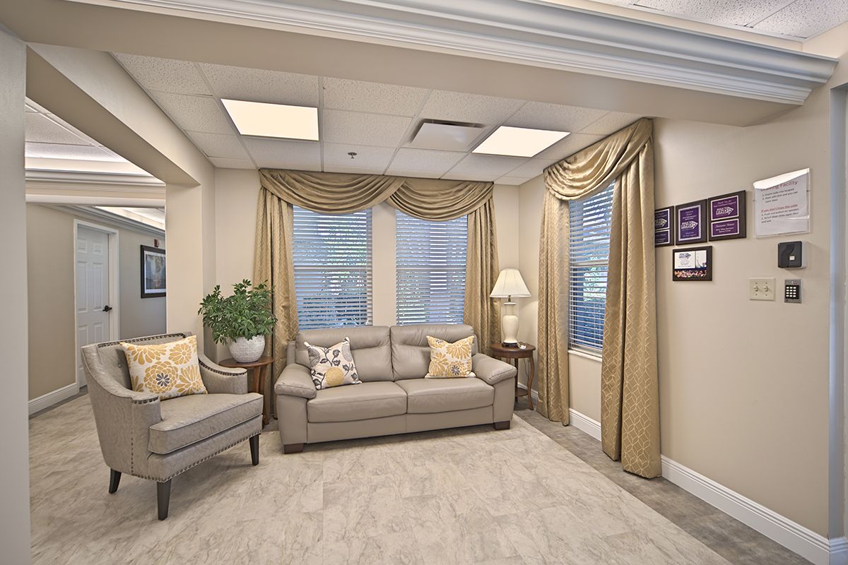 A cozy living room with elegant curtains, a comfortable sofa and armchair, a lamp, and decorative elements.