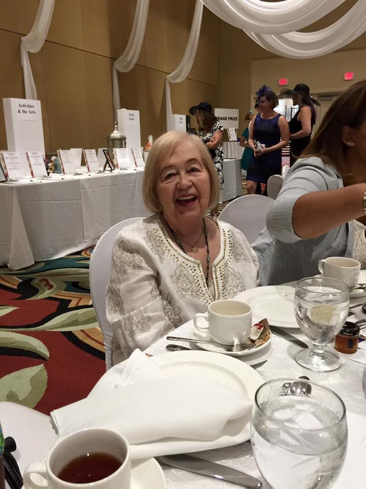 A joyful woman sitting at a dinner table during an event.