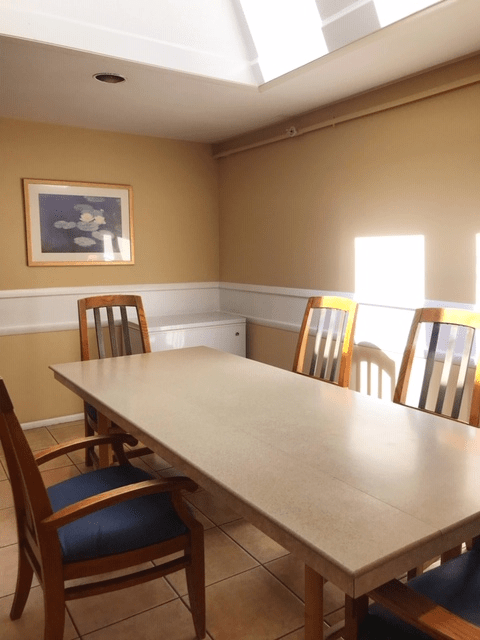 A simple conference room with a long table and several wooden chairs.