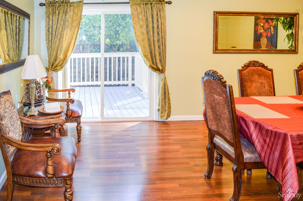 A cozy living and dining area featuring wooden floors, elegant furniture, and a sliding door leading to a deck.