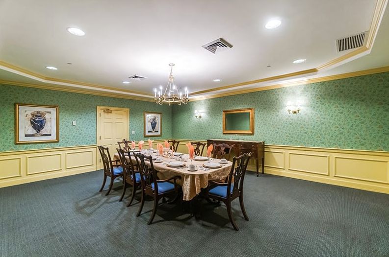A formal dining room with a long table, chairs, and elegant decor.