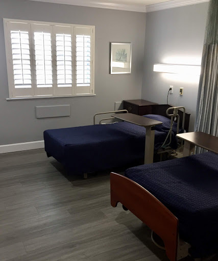 A sterile hospital room featuring two beds and medical equipment.