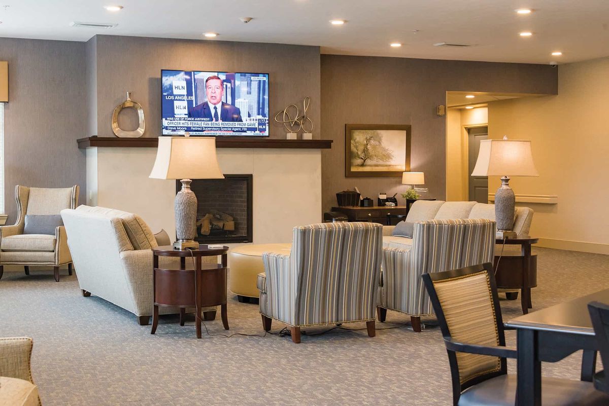 A cozy living room with comfortable seating, a fireplace, and a television mounted above.