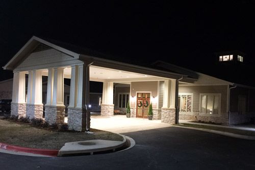 A well-lit building entrance with a covered walkway at night.