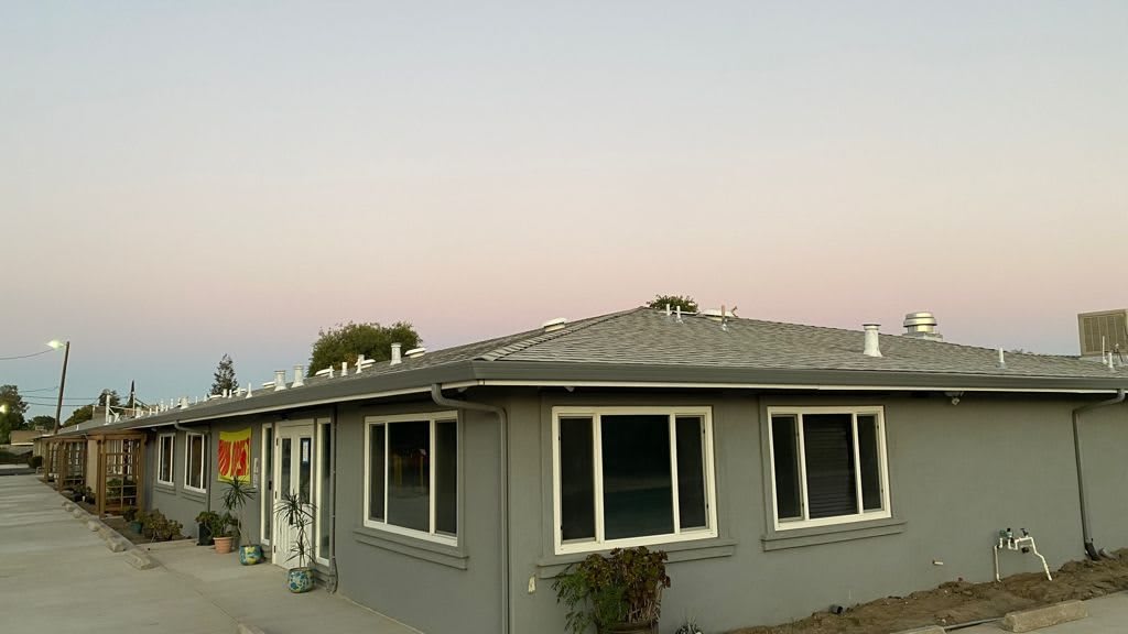 Sunset view of a residential house with large windows.