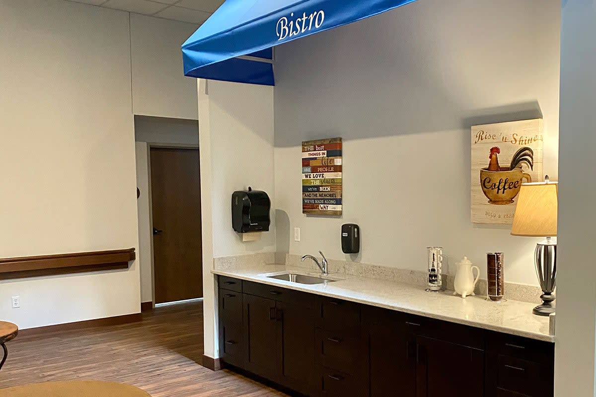 A small kitchenette area with a sink, counter, and blue awning in an office setting.