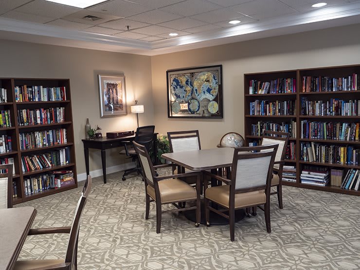 A cozy library room with bookshelves, a table, and chairs for studying.