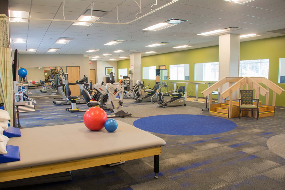 A spacious gym with various exercise equipment, including treadmills and a therapy area.