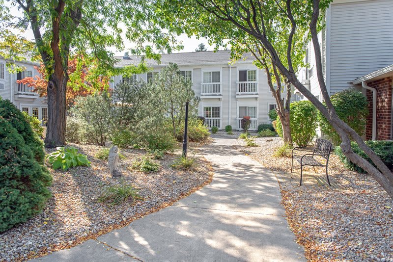 A scenic view of a house with a pathway surrounded by trees and gardens.