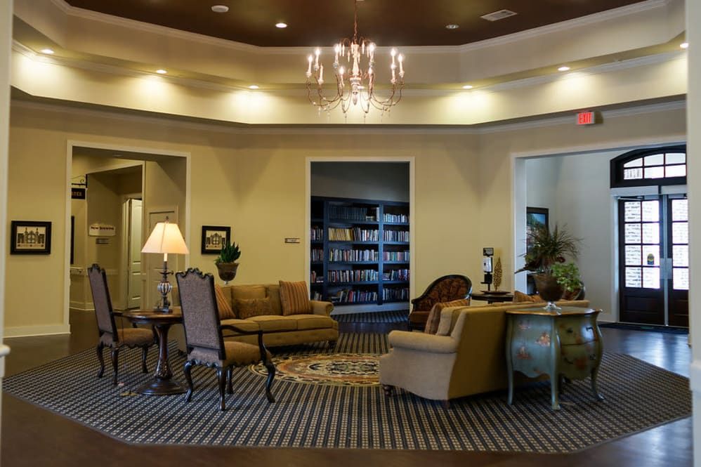 A cozy lobby area featuring comfortable seating, a chandelier, and a bookshelf.