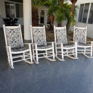 Four wooden rocking chairs with patterned cushions on a patio.