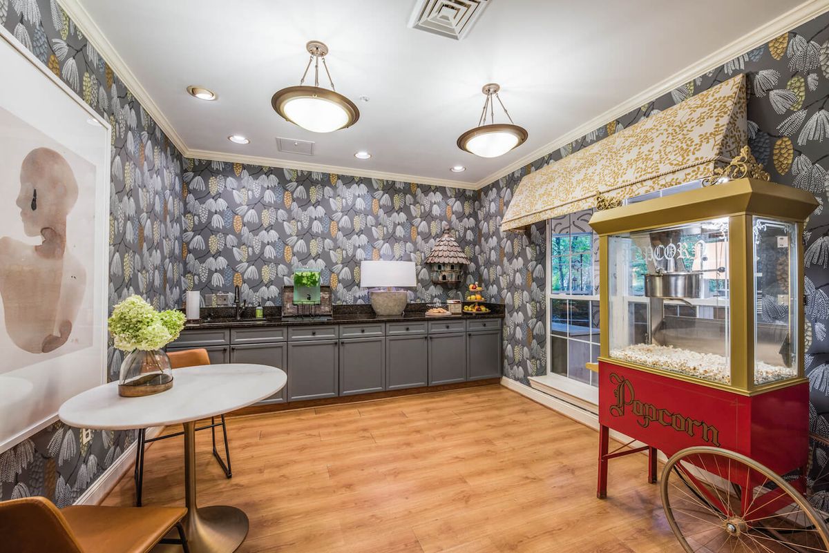 A stylish kitchen interior featuring modern wallpaper, a wooden floor, and a popcorn machine.